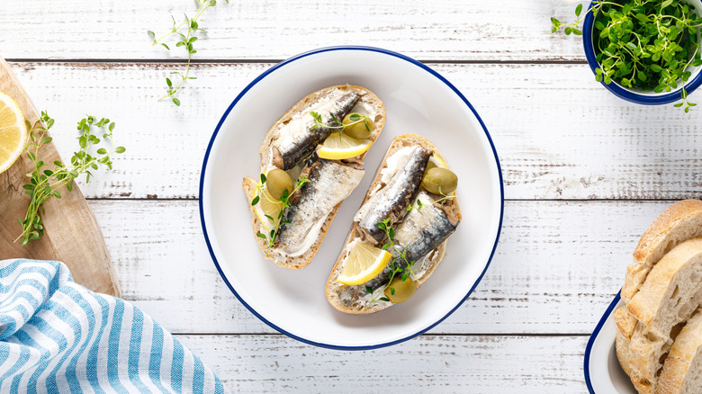 Sardine fillets on bread with lemon and olives.
