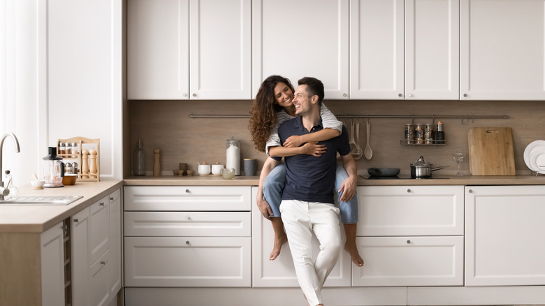 A couple embracing in a modern kitchen.