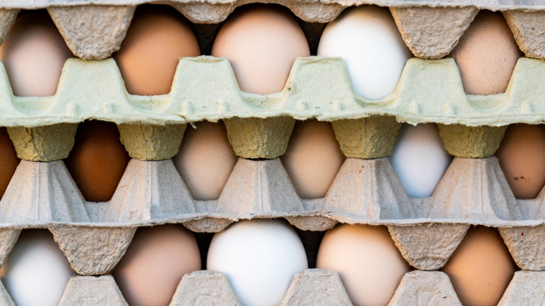 Stacked flats of eggs, various colors including brown, tan, and white