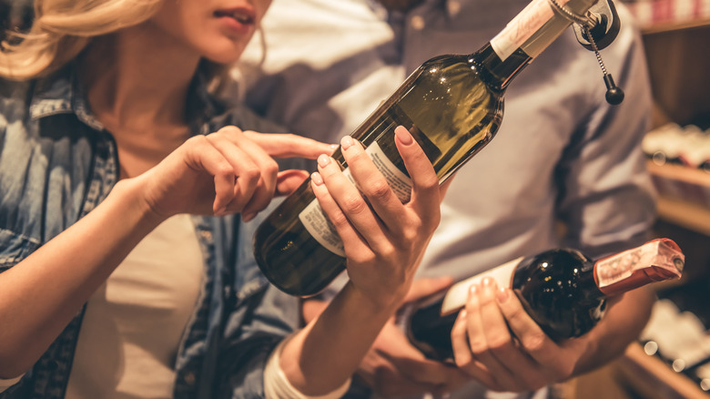 Two people comparing wines to buy at store