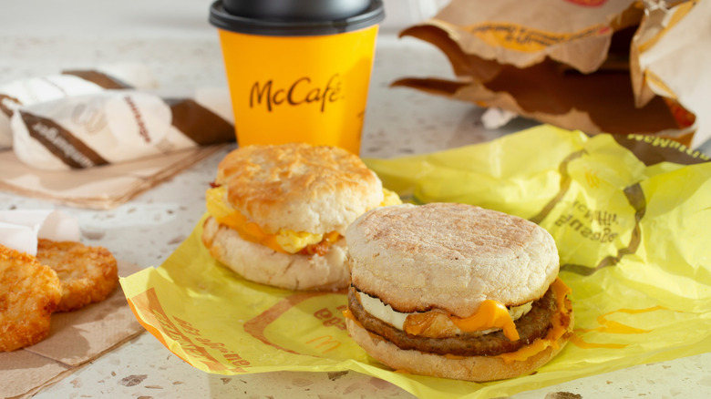 McDonald's breakfast sandwiches on yellow paper next to aMcCafé cup