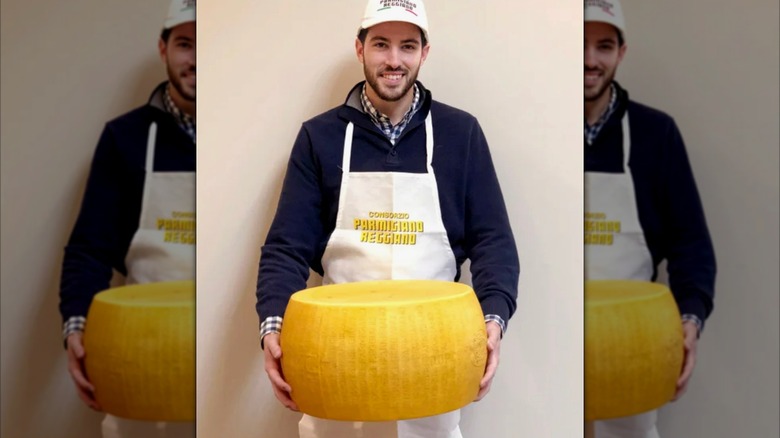 A cheesemaker holds the Costco Whole Wheel Parmigiano Reggiano