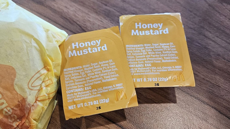 Two McDonald's honey mustard sauces sit on a table.