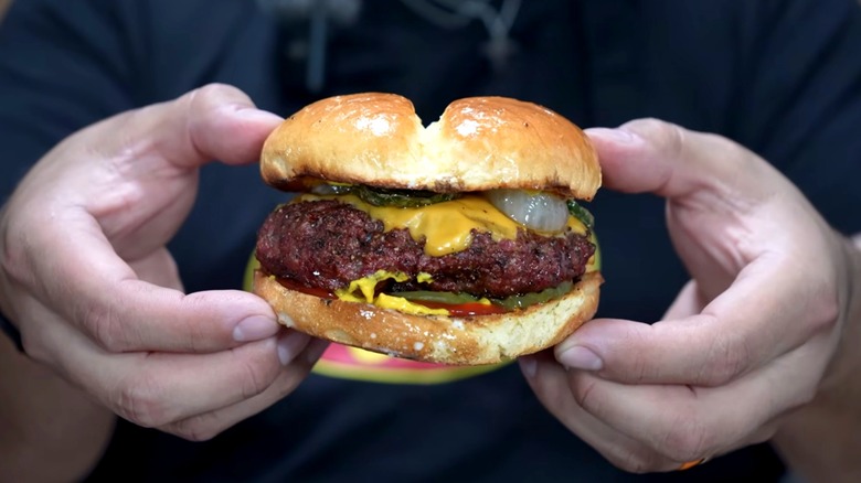 Hands holding a brisket burger