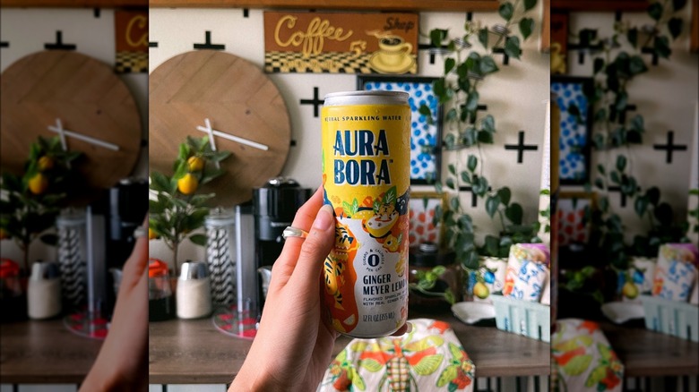 Person holding Aura Bora can of ginger meyer lemon