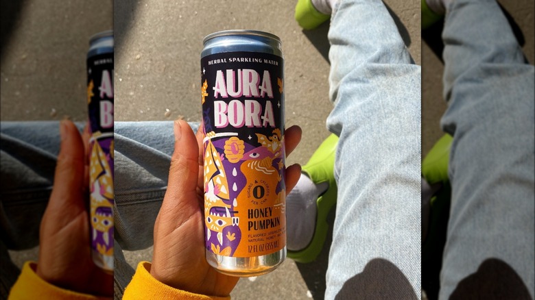 A person holds a can of sparkling water in honey pumpkin