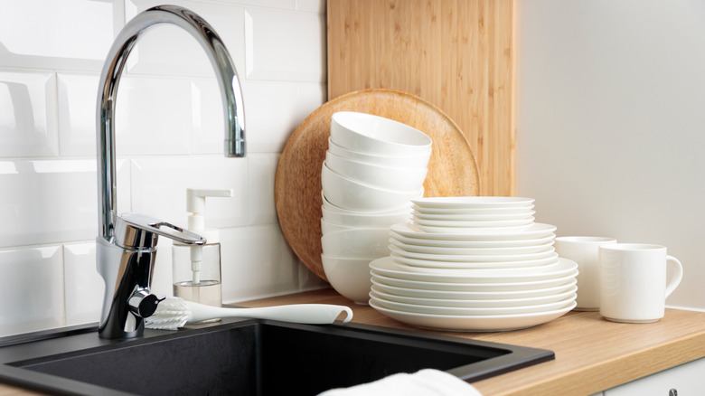 A modern kitchen sink with clean dishes next to it