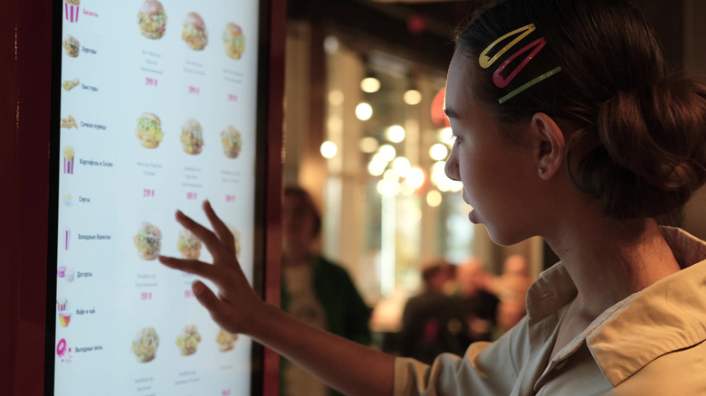 A woman orders from a fast food ordering kiosk
