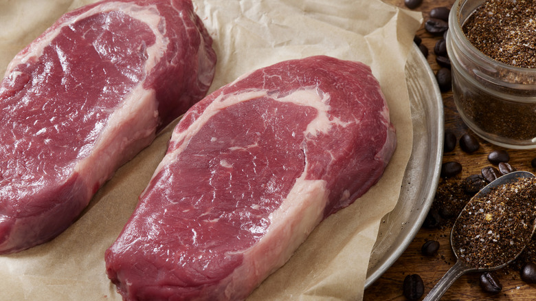 Raw steaks on parchment paper