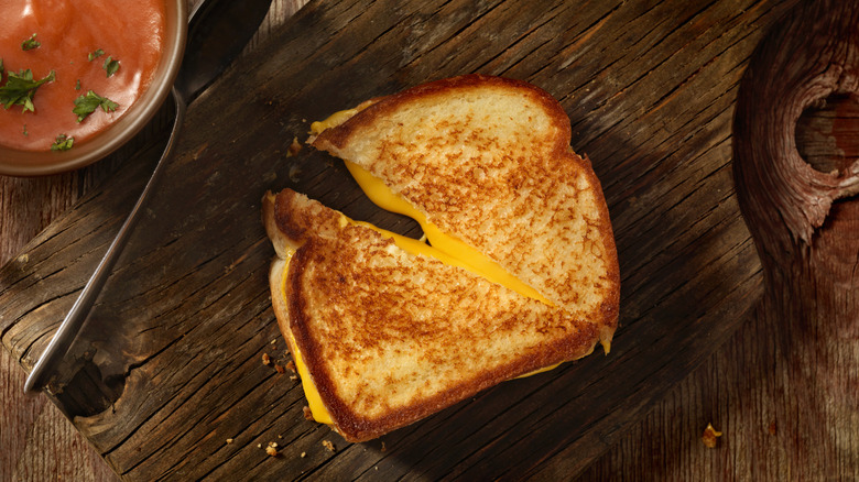 A grilled cheese sliced on a rustic wooden plank