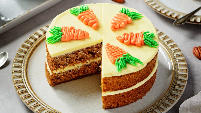 Layered carrot cake on a plate with one slice taken out