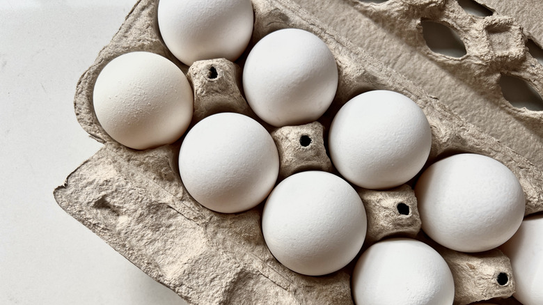 A close up on a carton of large, white eggs