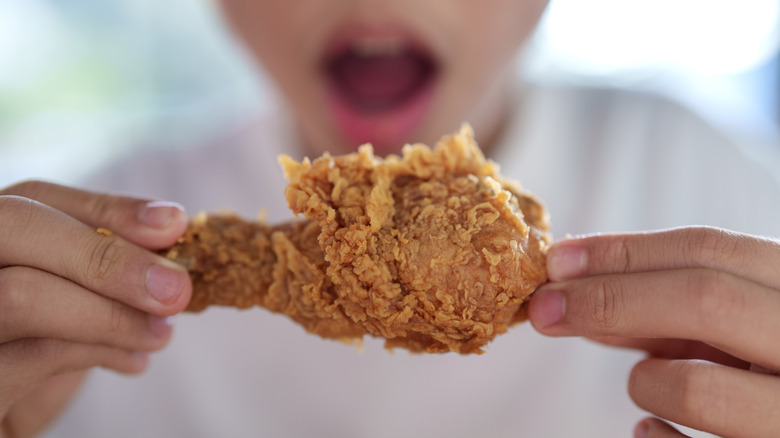 A person looks at a fried chicken drumstick with mouth agape