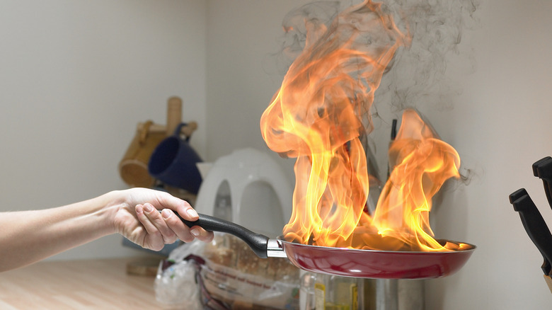 Person holding a flaming pan