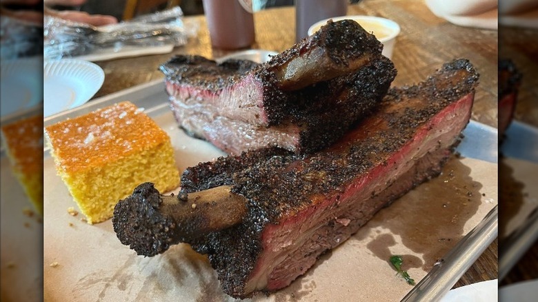 Large ribs and a piece of cornbread sit on a paper lined tray at Hometown Bar-B-Que in Red Hook, Brooklyn, New York