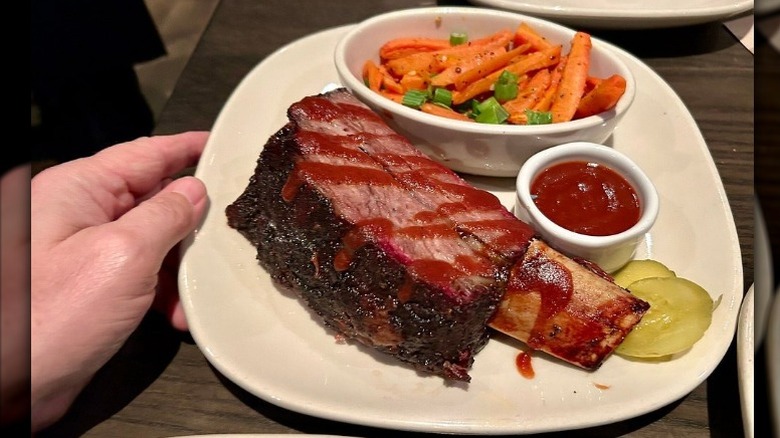 A person holds a plate with beef ribs and sides at Jack Stack Barbecue in Kansas City, Missouri