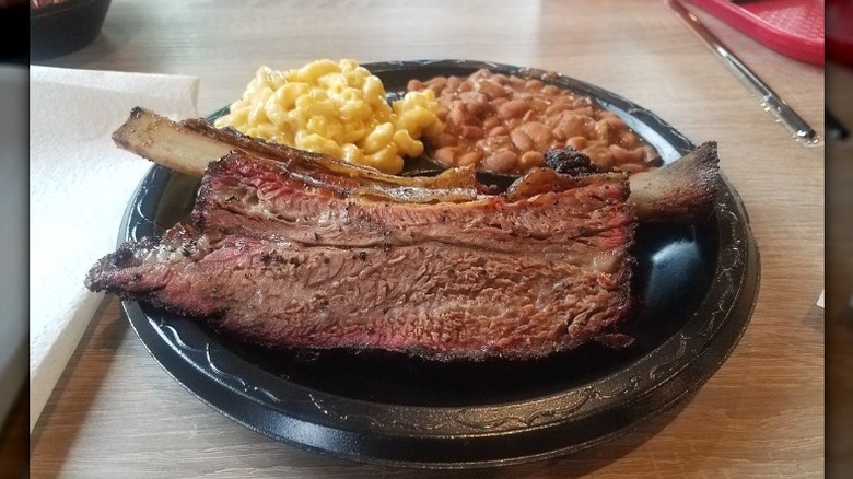 A plate of large beef ribs sits on a wooden table at Killen's Barbecue in Pearland, Texas