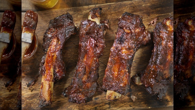 Barbecue beef ribs lie on a wooden serving board