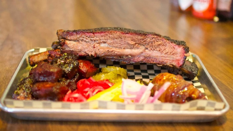 A large beef rib and sides sit on a paper lined tray at Roxie's Barbecue in Tahlequah, Oklahoma