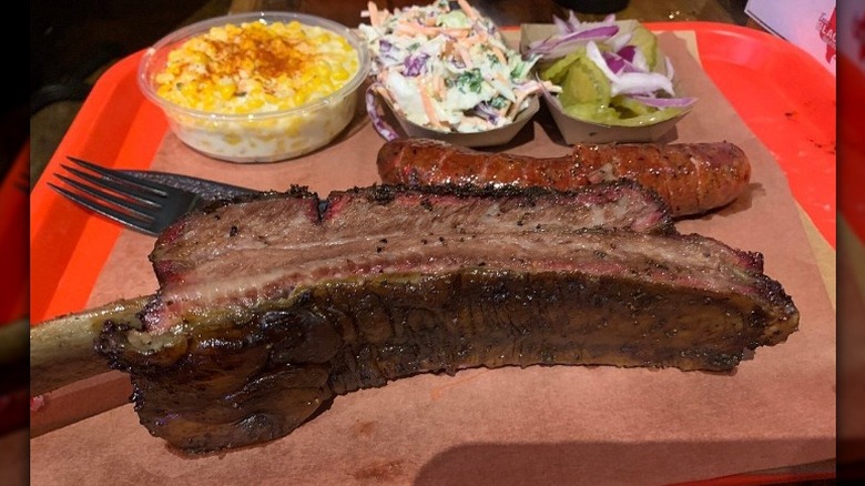 A large rib and sides sit on a paper lined tray at Terry Black's Barbecue in Austin, Texas