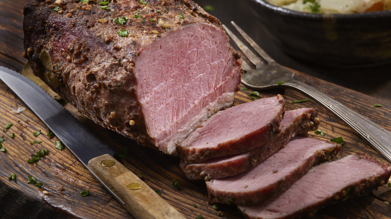 Sliced corned beef on a wooden board
