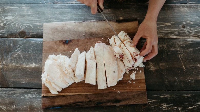 A home cook slices thick strips of beef fat to make tallow