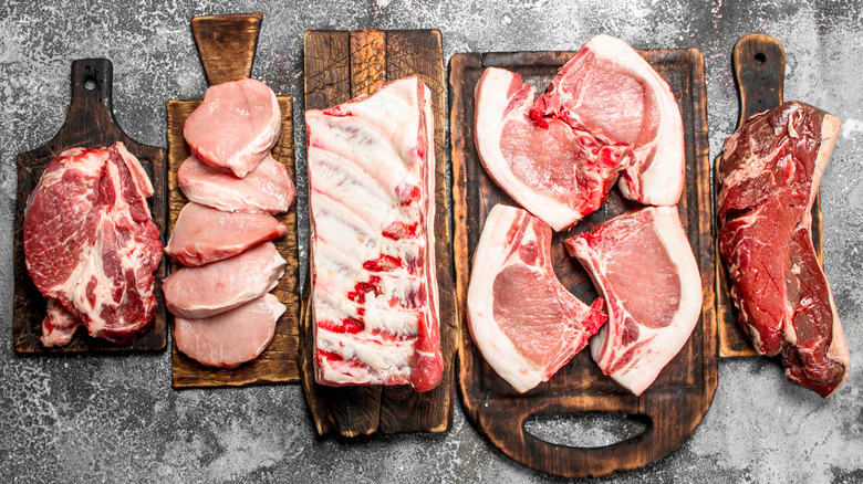 A mix of well-marbled beef and pork cuts on boards