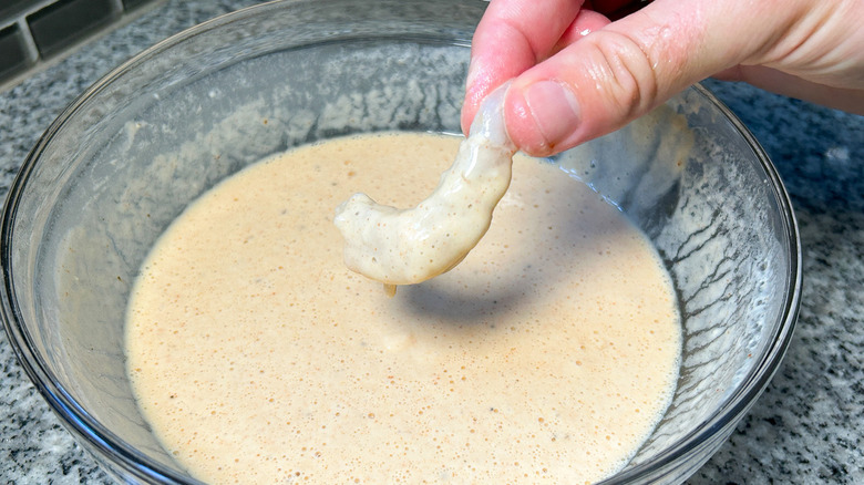 hand dipping shrimp in batter
