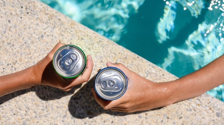 People holding cans by pool