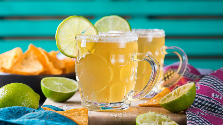 Two glasses of beer with beer salt on rim and garnished with lime wedges