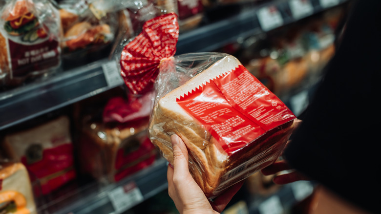 Customer grabs a loaf of bread from a grocery store shelf