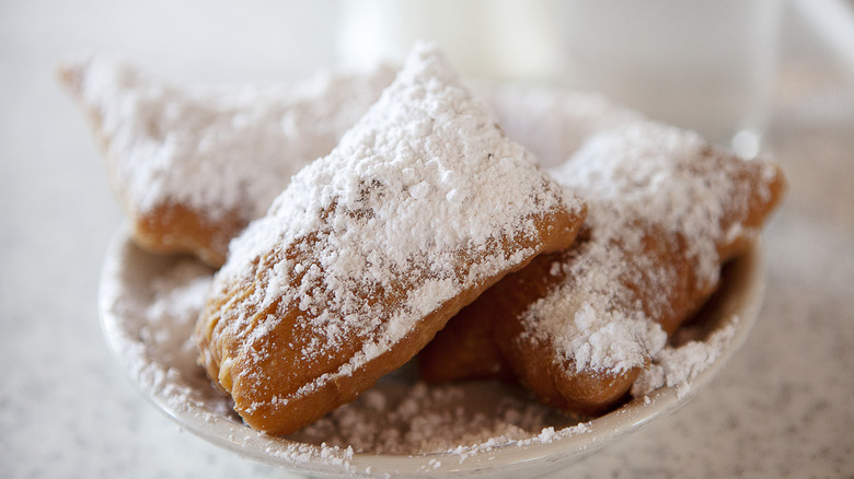 traditional beignet with powdered sugar on white plate