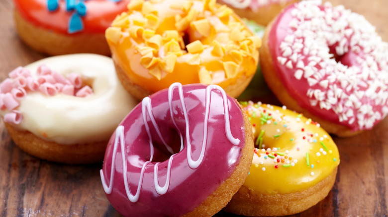 donuts with colorful frosting on wooden table
