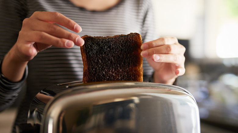 Woman pulling burnt toast from toaster