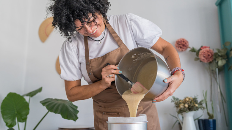 A baker pours cake batter into a cake tin