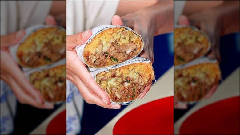 A person holding both halves of a MJ's breakfast burrito.