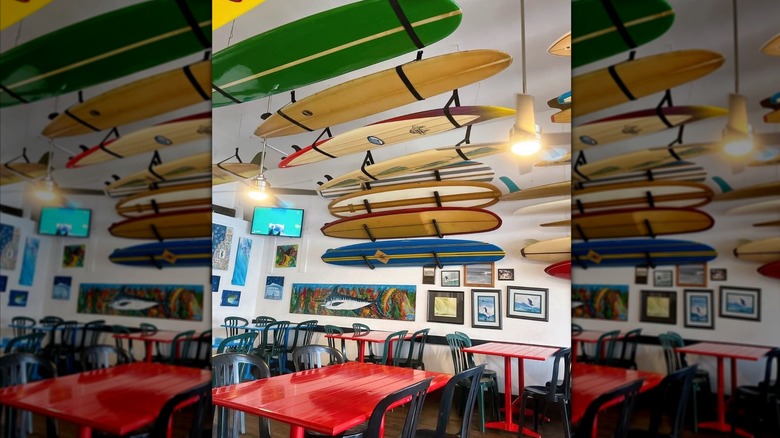 The interior of Taco Surf, with surf boards on the walls and ceilings and red tables.