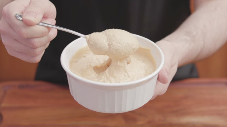 Someone takes a spoonful out of a fluffy peanut butter dip.