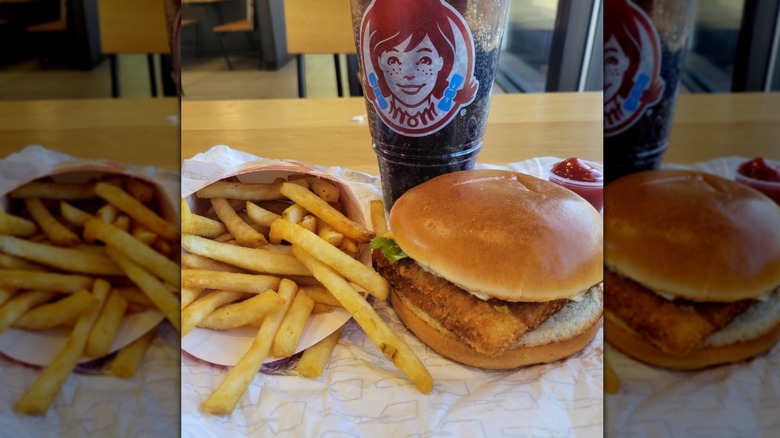 Wendy's fish sandwich meal with fries and a drink set out at a table
