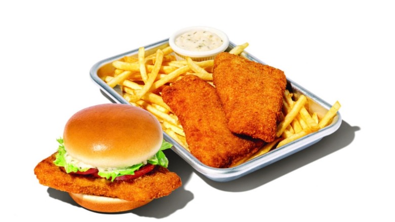 Whataburger's Whatacatch fish sandwich beside a platter of fried fillets with French fries