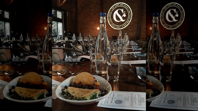 Plate of food at Cork and Craft with tables and sign behind it.