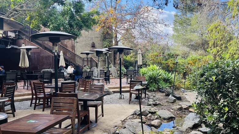 The outside patio at Stone Brewing World Bistro and Gardens, showing tables, greenery, and water.
