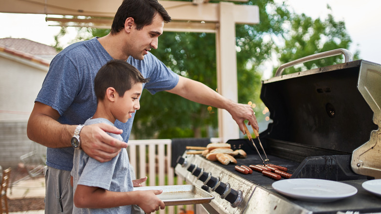 A dad mans the grill and teaches his child the basics of barbecuing.