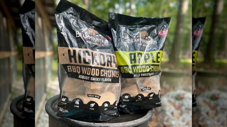 Bags of flavored wood chunks sit on a barrel outside.