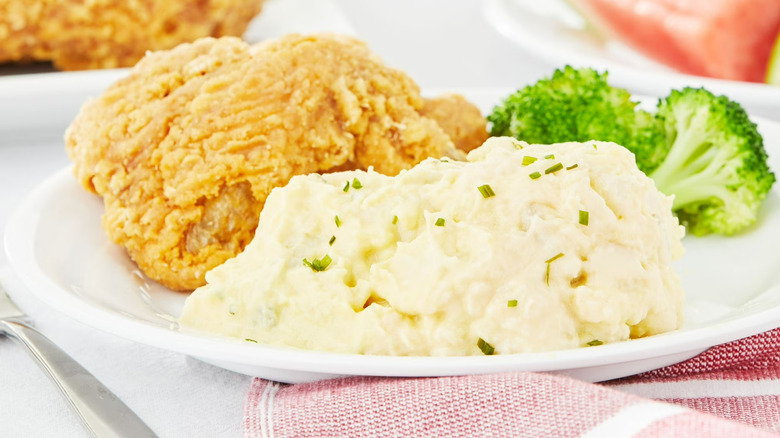 Walmart Freshness Guaranteed Mustard Potato Salad sitting on a plate with fried chicken and broccoli.