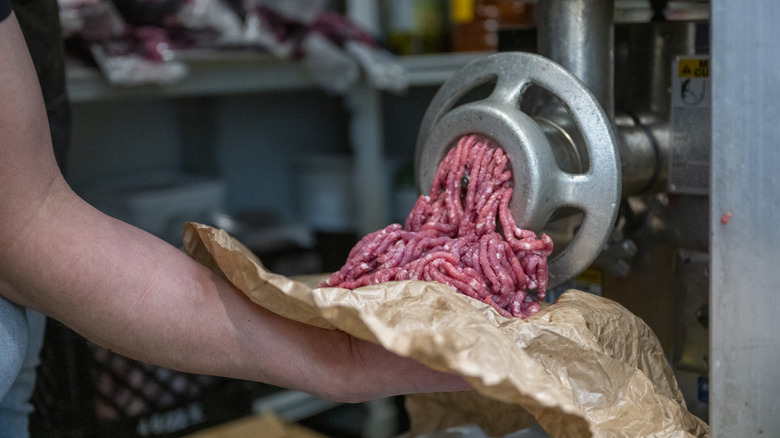 Butcher grinding meat onto paper