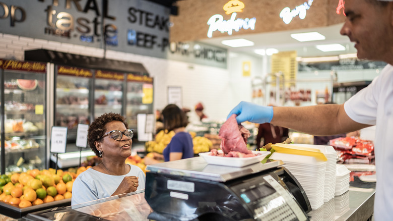 Butcher helping woman at meat counter