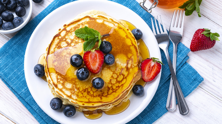 Stack of pancakes on a while plate.