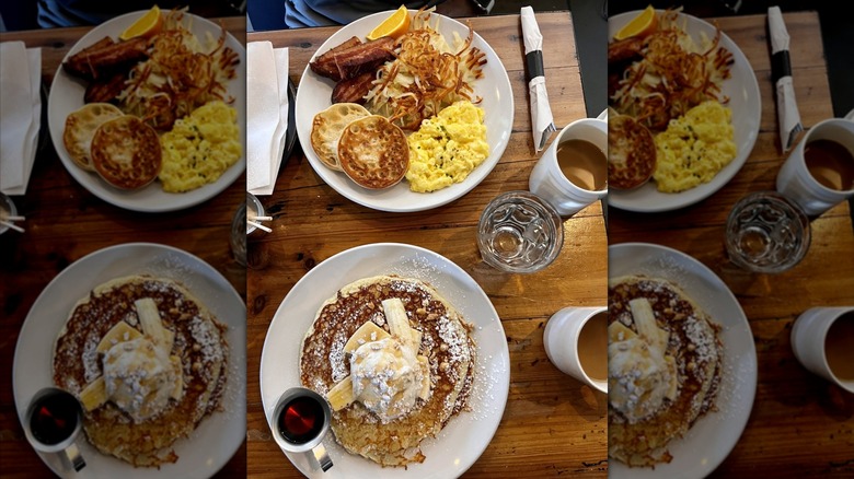 White plate with English muffin, eggs, and hash browns (top) and white plate with pancakes, bananas, whipped cream, and syrup (bottom).
