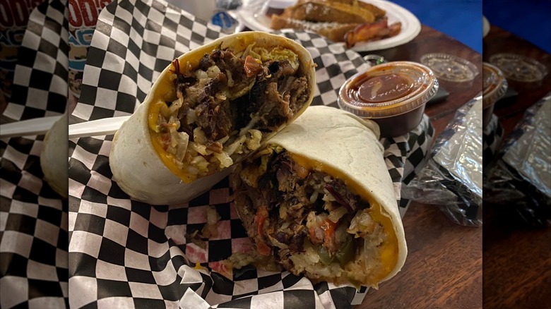 Brisket breakfast burrito on checkered paper.